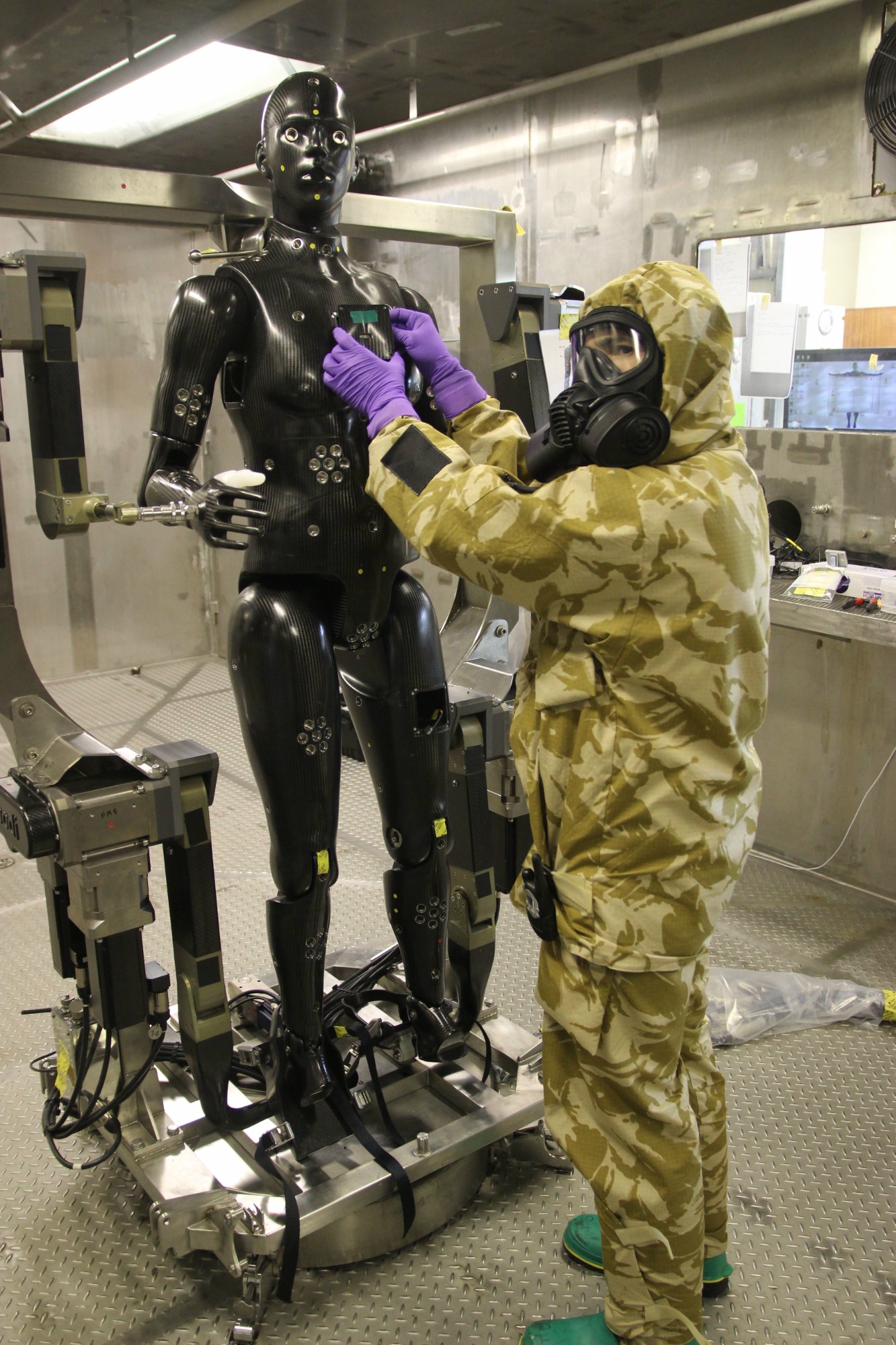Researcher in protective equipment working with laboratory robot